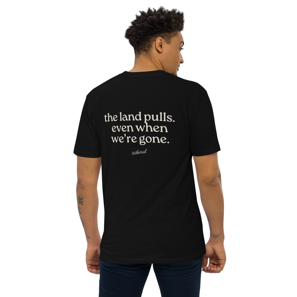 model wearing black the land pulls tee standing outdoors